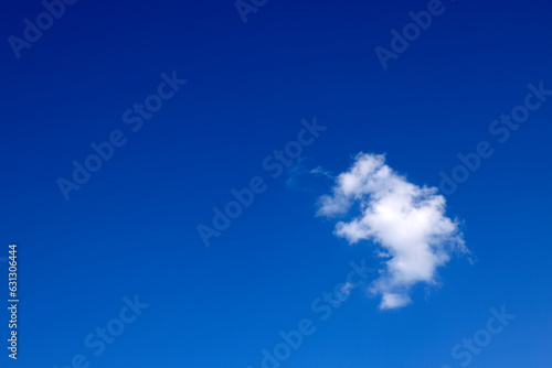 Single white cloud in blue sky. Bright blue sky with white puffy clouds