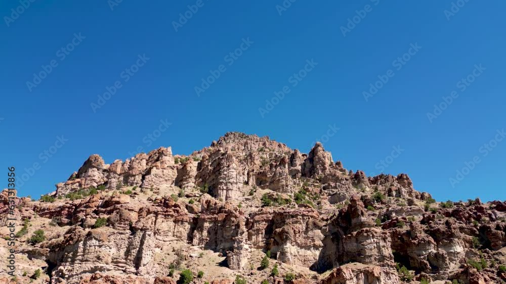 Aerial-Ascending over erosion carved rugged jagged rock formations against clear blue sky Aerial-Ascending over erosion carved rugged jagged rock formations against clear blue sky
