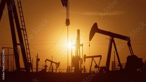 The sun rises behind a large oil field in California.