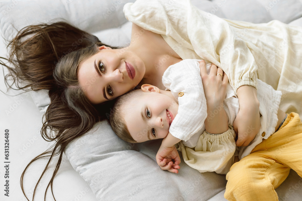 Top view of a beautiful woman and her cute little son smiling while lying on the floor. boy hug his mom Top view of a beautiful woman and her cute little son smiling while lying on the floor. boy hug his mom