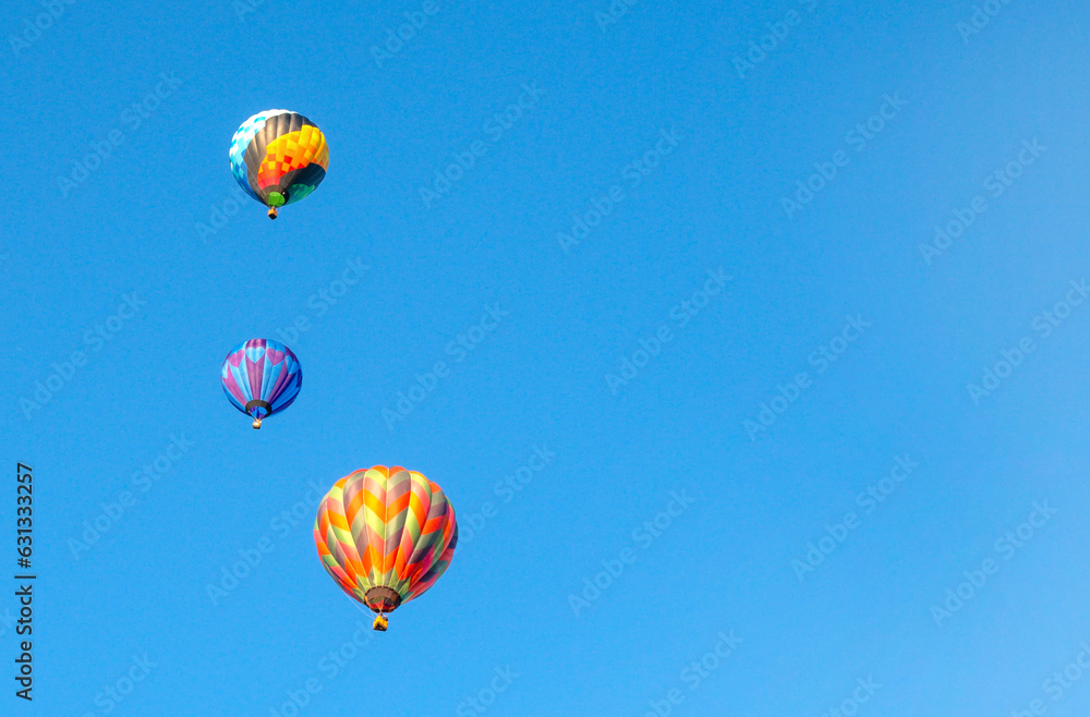 Fototapeta premium Three colorful hot air balloons and blue sky. Balloon Festival. Space for text 