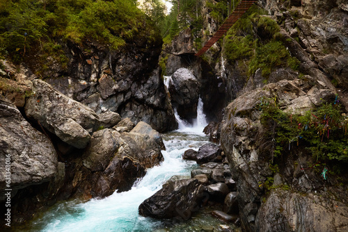 Waterfall on the mountain river Kyngarga near the village of Arshan in the Republic of Buryatia. At the top there is a suspension bridge for tourists. Extreme outdoor recreation. photo