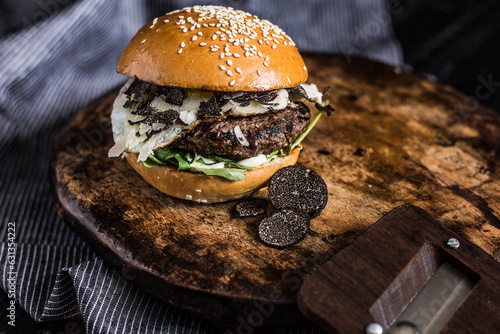 Close-up of truffle burger with fried egg decorated on a wooden plate and dark background, Expensive fast food