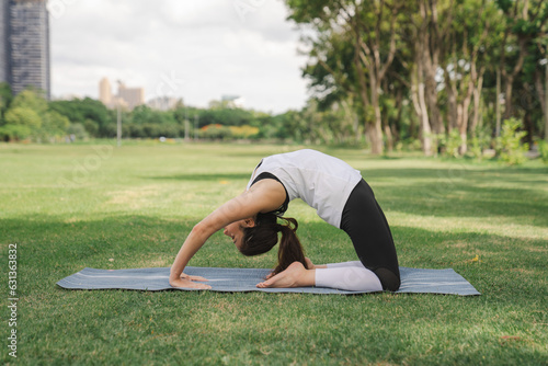 young woman have a beautiful body, Playing yoga in an elegant posture, in the green park, a concept to people's recreation and health care concept. blurred background