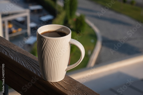 coffee cup on wooden balcony railing at sunrise