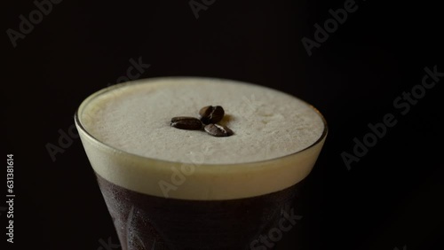 Coffee beans being placed as garnish on espresso martini cocktail