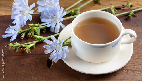 Chicory drink in a white mug with chicory flowers next to it on a wooden board.
