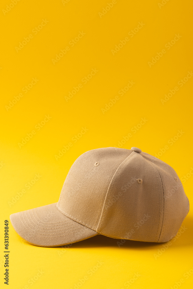 Fototapeta premium Cream baseball cap and copy space on yellow background