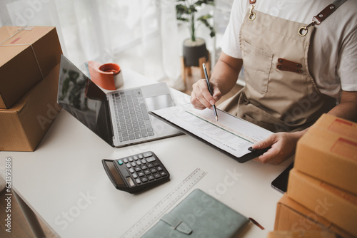 Man working, online shop owner checking orders from websites on the internet to confirm orders with customers who have ordered them and packing them for delivery. Concept of selling products online.