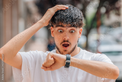 young man looking at watch scared on the street, punctuality