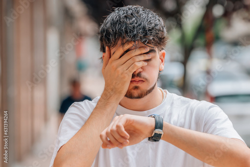young man looking at watch scared on the street, punctuality photo