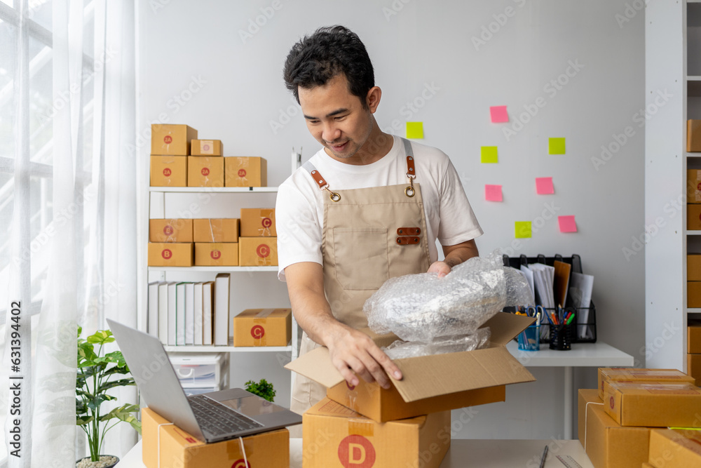 Male owner of an online store packs products into parcel boxes based on orders from online sales sites, packs products for delivery to addresses via private courier service. Product packaging concept. Male owner of an online store packs products into parcel boxes based on orders from online sales sites, packs products for delivery to addresses via private courier service. Product packaging concept.