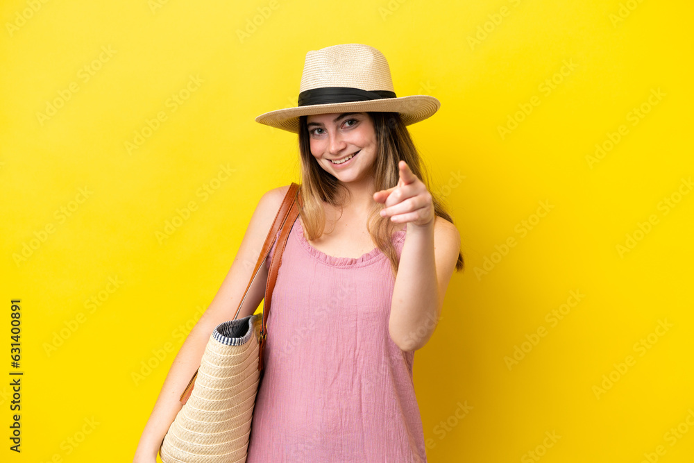 Young caucasian woman holding a beach bag isolated on yellow background pointing front with happy expression Young caucasian woman holding a beach bag isolated on yellow background pointing front with happy expression