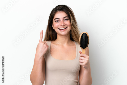 Young woman with hair comb isolated on white background pointing up a great idea