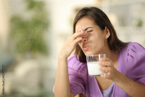 Fotografie Woman smelling expired milk at home