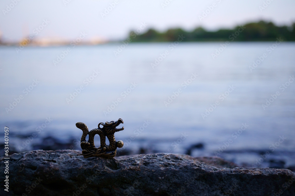 Dragon figurine on the background of the river. An esoteric and religious symbol.