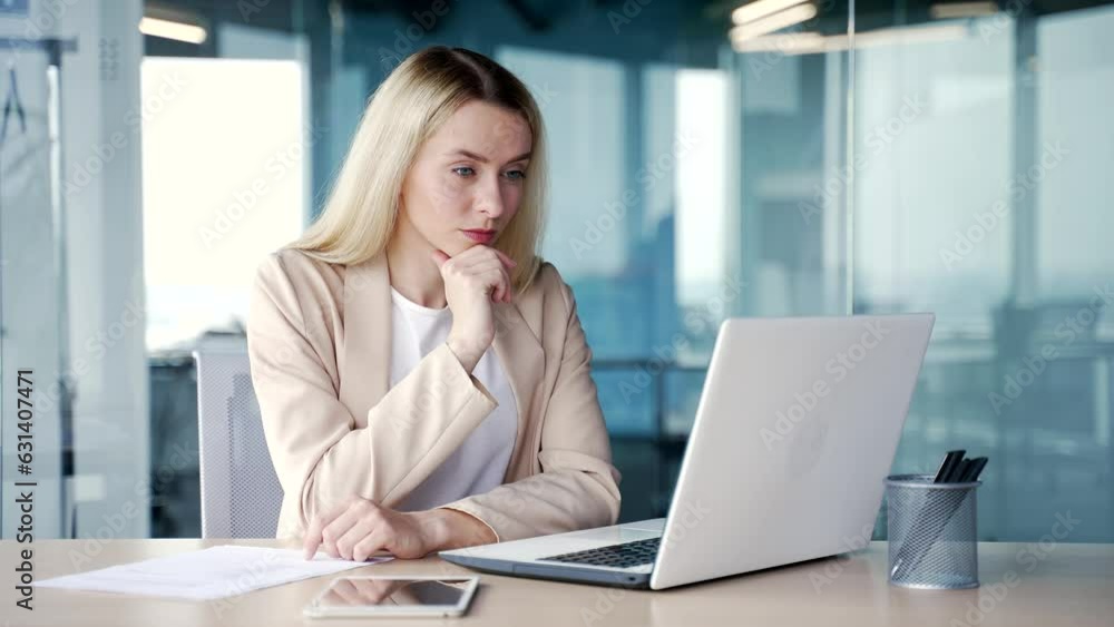 Thoughtful young businesswoman working on laptop while sitting at workplace in modern office. Serious concentrated female manager thinks about solving a problem, analyzes information on the Internet Thoughtful young businesswoman working on laptop while sitting at workplace in modern office. Serious concentrated female manager thinks about solving a problem, analyzes information on the Internet
