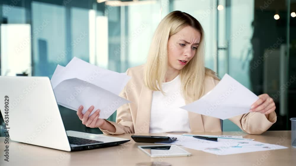 Disappointed young businesswoman having difficulty with paper work while sitting at workplace in modern office. Confused female blonde employee looks at the documents and cannot understand the problem Disappointed young businesswoman having difficulty with paper work while sitting at workplace in modern office. Confused female blonde employee looks at the documents and cannot understand the problem