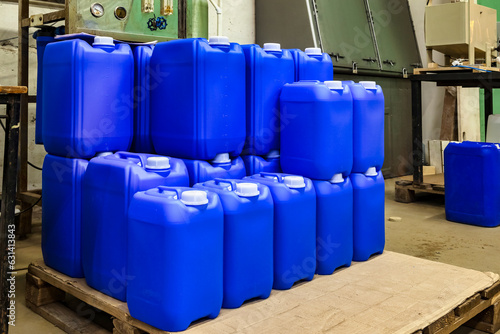 Warehouse storage of chemical liquids. Rows of liquid containers standing on wooden pallets. Background of storage cans in the warehouse. Concept of warehousing and stored of goods. Copy ad text space