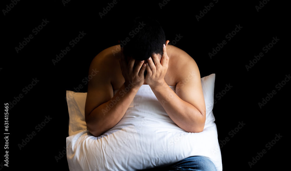 Shirtless middle-aged man sitting stressed out holding his head with his hands and hugging white pillow on black background . Depression, anxiety and mental health concept Shirtless middle-aged man sitting stressed out holding his head with his hands and hugging white pillow on black background . Depression, anxiety and mental health concept