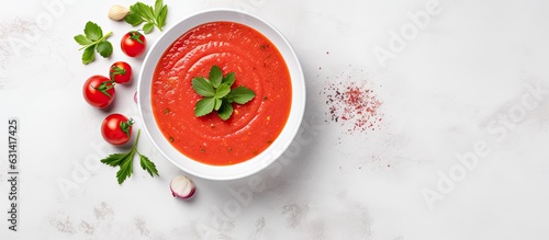 Gazpacho soup presented in a bowl on a light stone background with space for text. It is a chilled