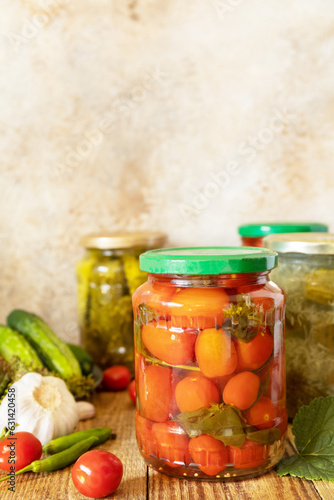 Healthy homemade fermented food. Salted pickled cucumbers and tomatoes preserved canned in glass jar. Home economics, autumn harvest preservation. Copy space.