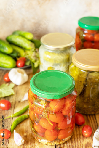 Salted pickled cucumbers and tomatoes preserved canned in glass jar. Home economics, autumn harvest preservation. Healthy homemade fermented food.