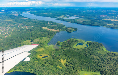 View of airplane wing, blue skies and green land and river during landing. Airplane window view.