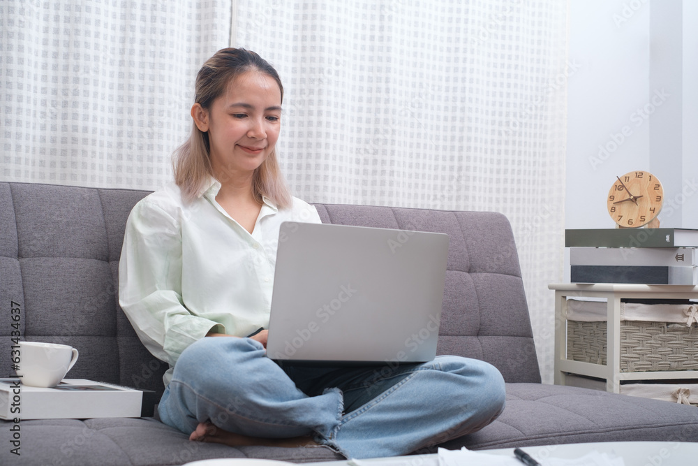 Smiling young woman using laptop and sitting on sofa at home, beautiful girl shopping or chatting online in social network, having fun, watching movie, freelancer working on computer project. Smiling young woman using laptop and sitting on sofa at home, beautiful girl shopping or chatting online in social network, having fun, watching movie, freelancer working on computer project.