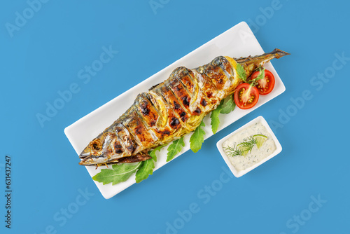 grilled mackerel with lemon and tomatoes on a blue background for the menu, studio shooting
