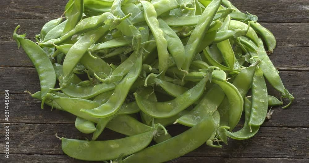Raw sugar snap pea heap on wooden rustic table. Table spin. Raw sugar snap pea heap on wooden rustic table. Table spin.