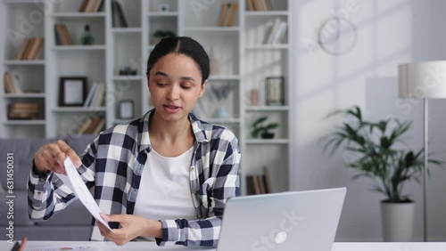 Attractive young woman works from home, has a video call with colleagues, shows graphs. Attractive young African American female student studying at home, giving a work presentation.