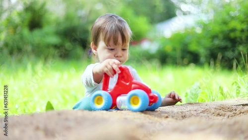 A child rolls a car on the street . Children's games. Outdoor games . Happy childhood. Children 's toys . Colorful cars . One children