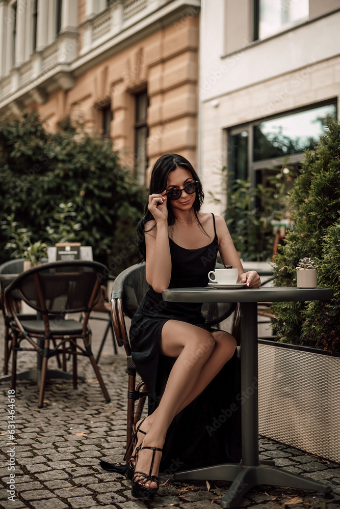 Attractive woman with a cup of coffee sitting at a table on the street