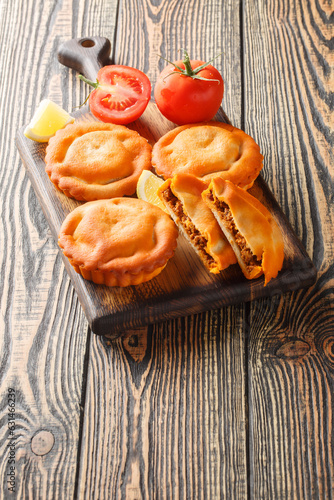 French dish tielles with calamari and tomatoes filling closeup on a wooden board on the table. Vertical photo