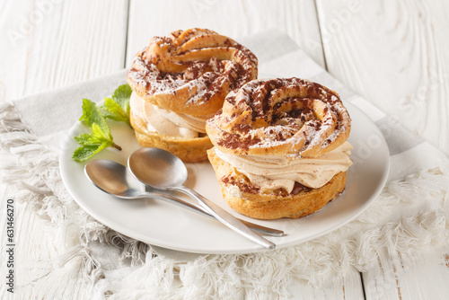 Paris-Brest is an indulgent iconic French dessert made of choux pastry and hazelnut praline closeup on a plate on the wooden table. Horizontal