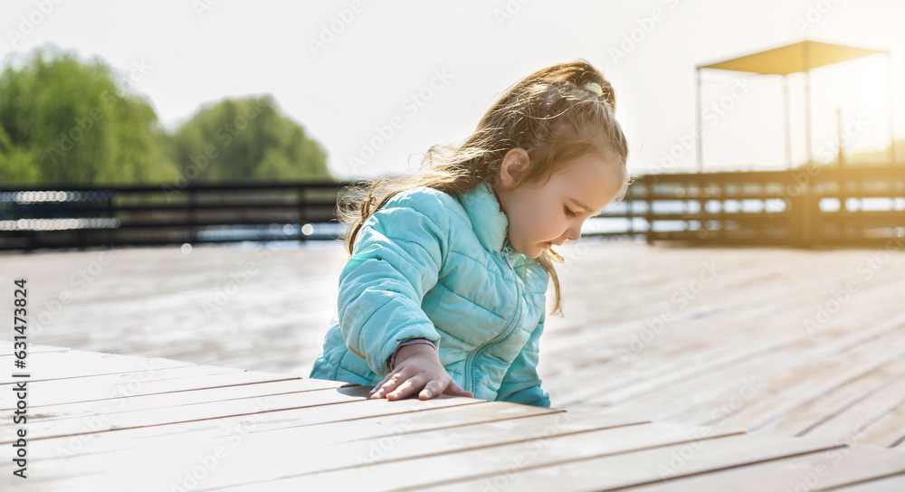 child for a walk. A cute little girl walks on a wooden pier by the river child for a walk. A cute little girl walks on a wooden pier by the river
