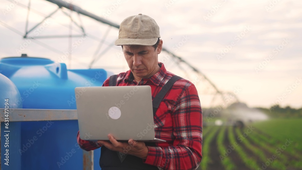 irrigation agriculture. a male farmer works on a laptop in a field with corn. irrigation agriculture business concept. farmer scientist studying corn. healthy natural foods concept lifestyle irrigation agriculture. a male farmer works on a laptop in a field with corn. irrigation agriculture business concept. farmer scientist studying corn. healthy natural foods concept lifestyle