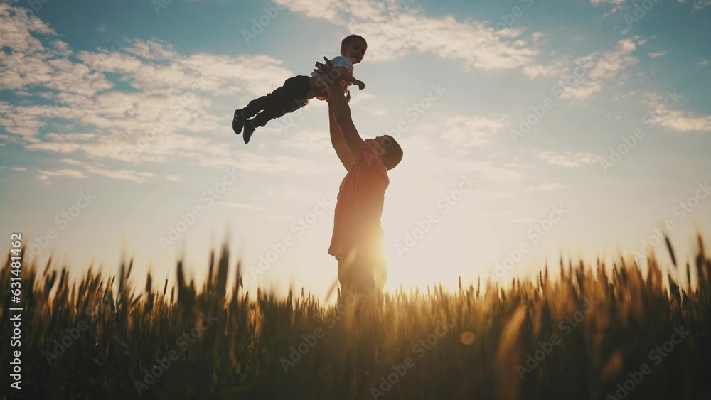 father playing with son in the park. dad throws baby up into the sky