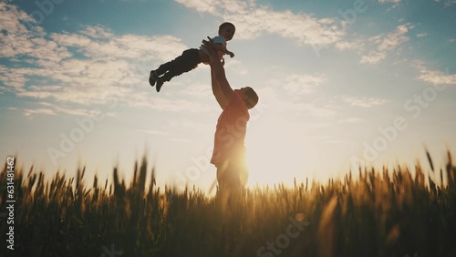 father playing with son in the park. dad throws baby up into the sky silhouette in the field in nature in the park. happy family kid concept. father day. baby boy dream playing with father silhouette