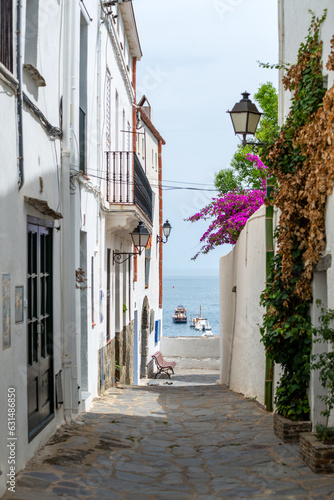 Fototapeta Naklejka Na Ścianę i Meble -  Cadaqués, view from a narrow street with traditional white houses to the port with boats - June 10, 2018 - Costa Brava, Catalonia, Spain