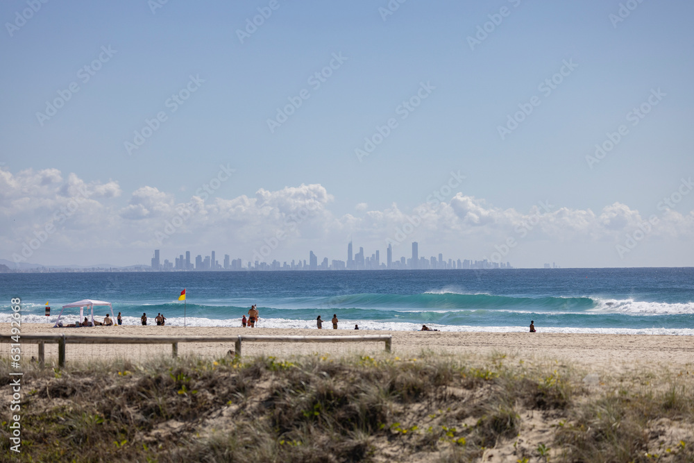 Tourists on Coolangatta beach along the Gold Coast, with skyline in background in Queensland, Australia