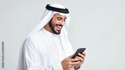 Happy Arab man in traditional attire, enjoying mobile banking services on his smartphone.