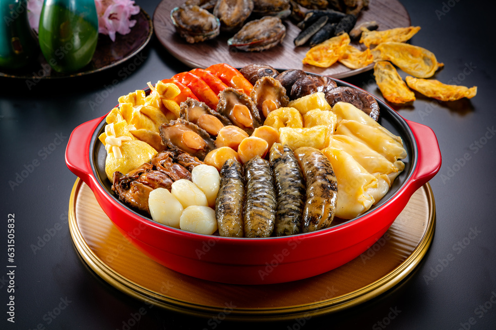 traditional asian luxury treasure premium seafood Peng cai abalone, sea cucumber, scallop, prawn, oyster, mushroom in hot clay pot on red table for Chinese new year cuisine halal banquet food menu