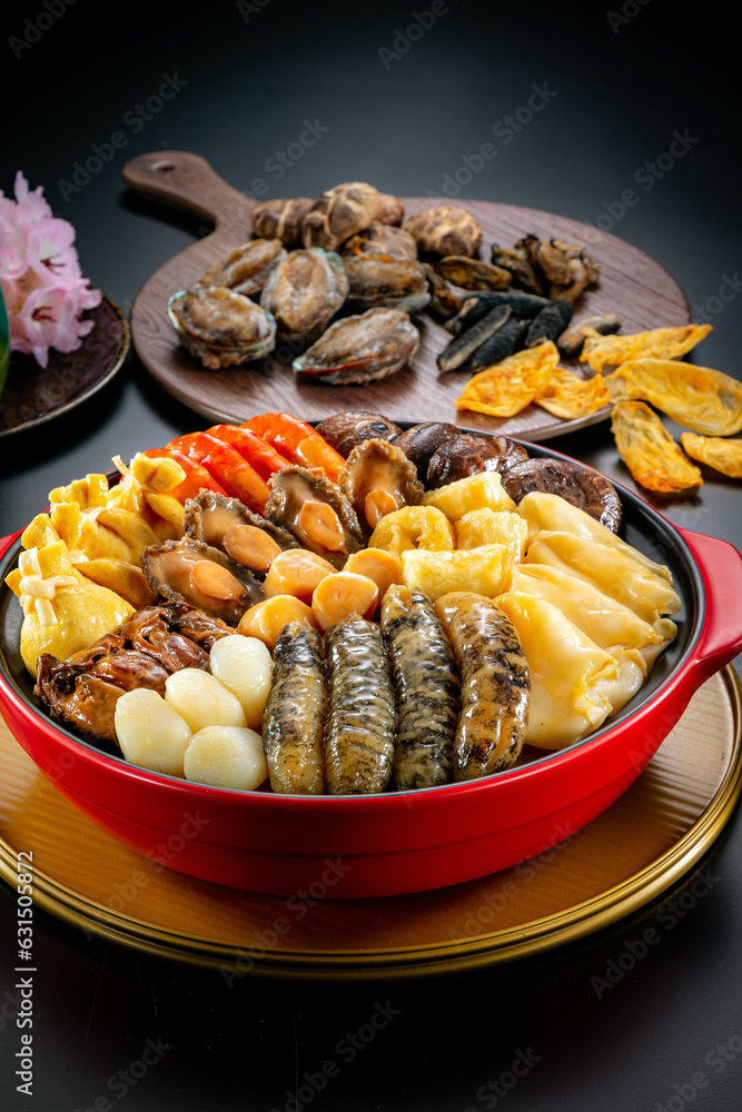 traditional asian luxury treasure premium seafood Peng cai abalone, sea cucumber, scallop, prawn, oyster, mushroom in hot clay pot on red table for Chinese new year cuisine halal banquet food menu