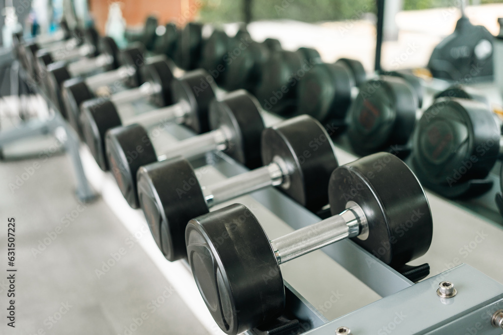 Obraz premium Row of Dumbbell indoor gym. Weight training equipment and bodybuilder concept. Sport club with heavy Weight workout for Muscular.