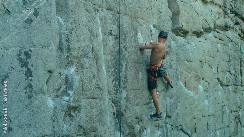strong man rockclimber climbing on tough sport route, searching, reaching and gripping hold. climber makes a hard move and clipping rope. outdoors rock climbing and active lifestyle strong man rockclimber climbing on tough sport route, searching, reaching and gripping hold. climber makes a hard move and clipping rope. outdoors rock climbing and active lifestyle