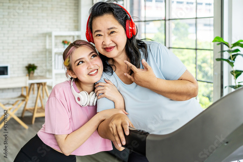 Happy Asian daughter and elderly mother in sportswear exercise together at home both of them smiled happily. Retired woman enjoy workout. Family relationship and senior people health care concept