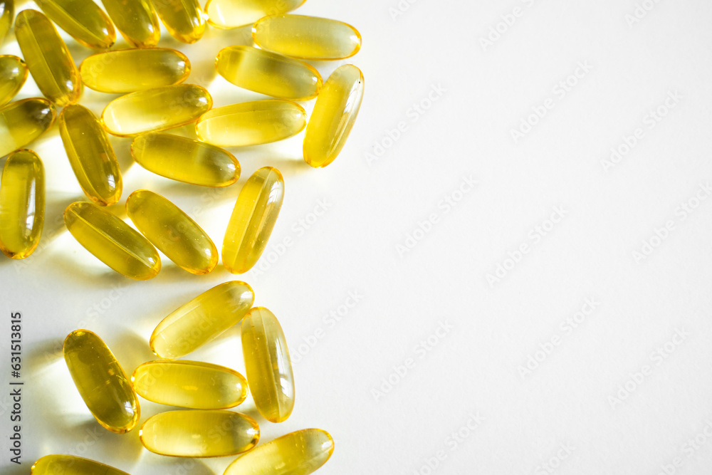 Fototapeta premium Oil filled capsules, softgel of food supplements. Fish oil, omega 3. Yellow softgels on white, copy space.
