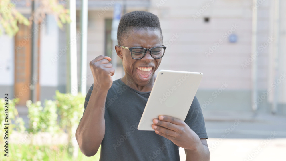 Young African Man Celebrating Success on Tablet Outdoor Young African Man Celebrating Success on Tablet Outdoor